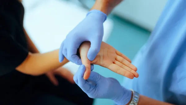 Close up of gloved hands inspecting patient's thumb