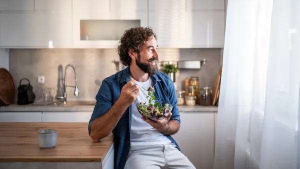 Man sitting in kitchen eating a salad