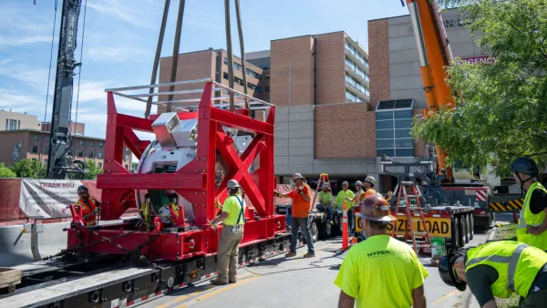 Proton therapy machine being lowered via crane.