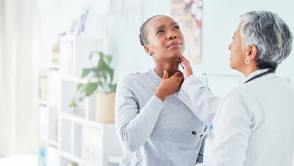 Doctor feeling woman's throat