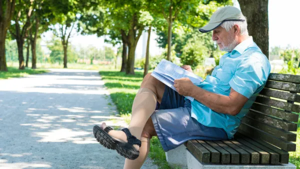 Man wearing compression socks, sitting on park bench reading