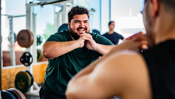 Man doing squats in the gym with a trainer