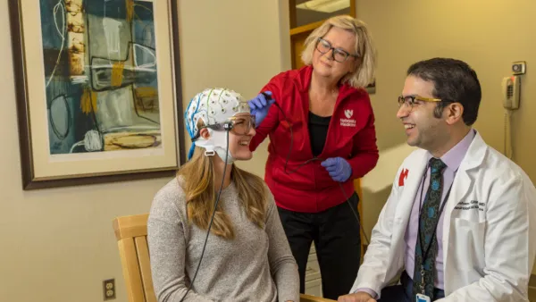 Doctor and nurse talking to patient with MEG helmet