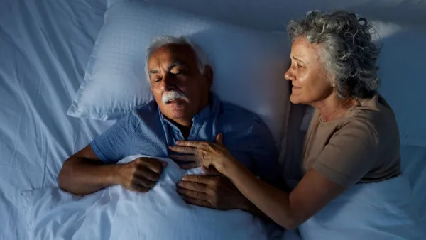 Woman in bed nudging her snoring husband
