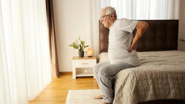 Man sitting on the side of the bed with back pain