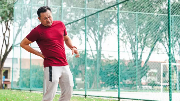 Man at park, holding hip in pain