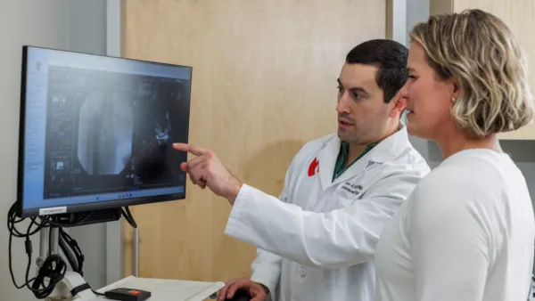 Beau Kildow, MD pointing at medical image on computer with patient Michelle Chastain