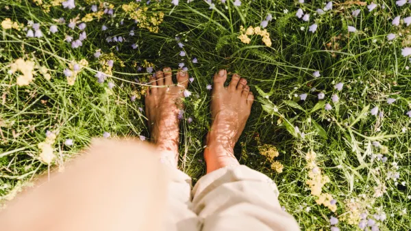 POV looking down at woman's bare feet standing in grass