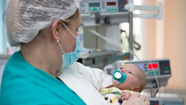 Woman in scrubs holding baby in NICU