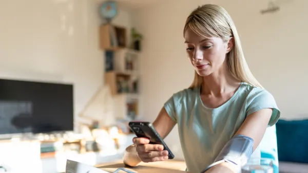 Woman checking blood pressure and holding phone