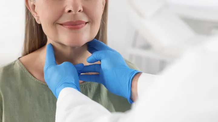Doctor feeling woman's throat