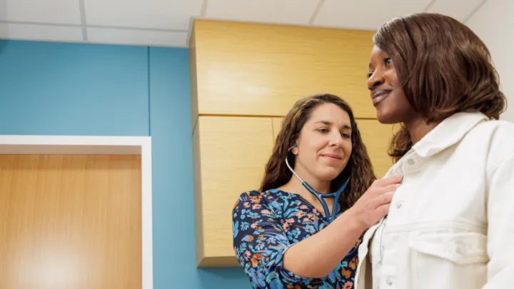 Provider listening to young woman's heart