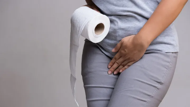 Close up of woman holding toilet paper and groin