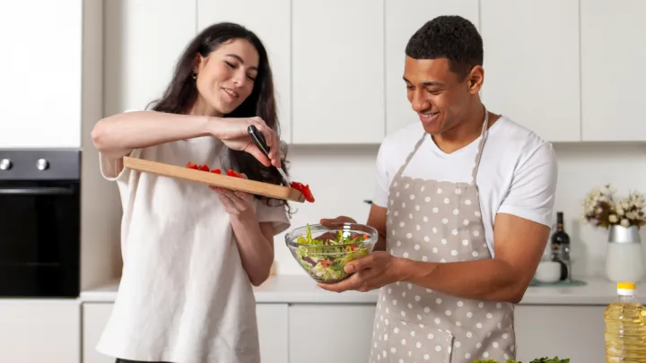 Man and woman in kitchen making a salad