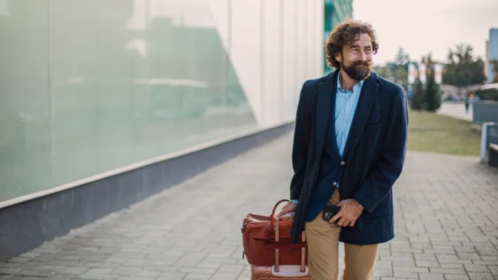 Man with suitcase holding groin