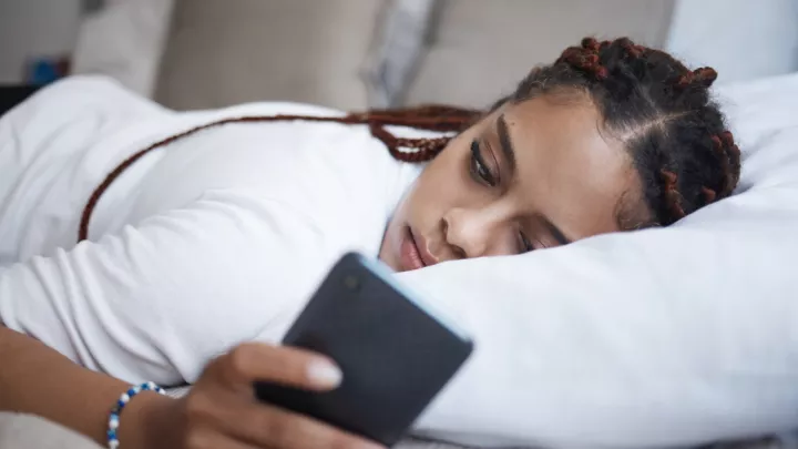 Depressed woman laying on the couch on her phone