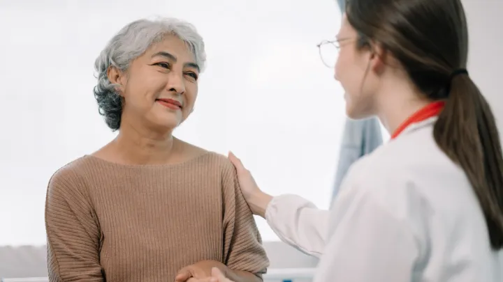 Doctor talking to older woman, putting her hand on her shoulder