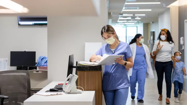 A picture of a nurse standing at a nurse's station