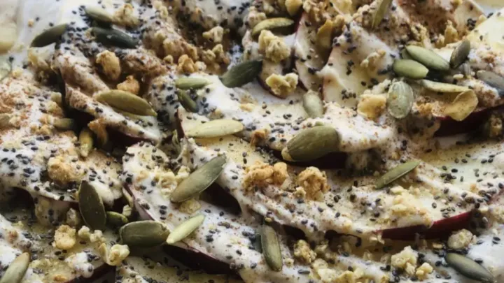 Plate of sliced apples covered in seeds, Greek yogurt and honey