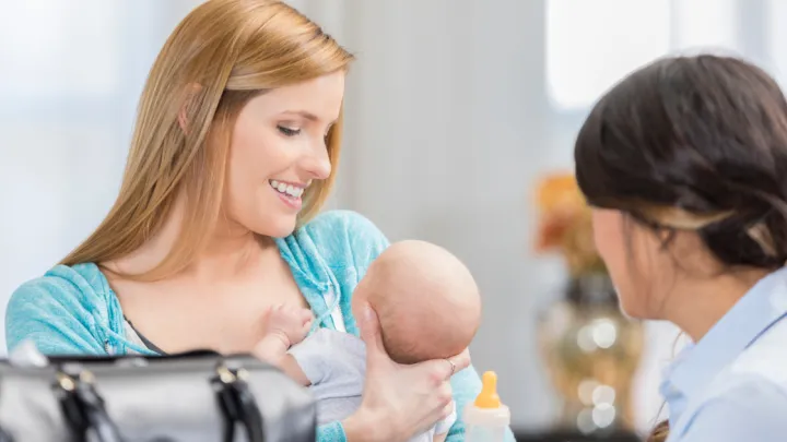 Woman holding an infant talking to lactation consultant