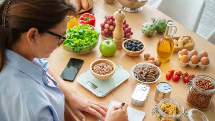 Woman planning, writing weekly meals on a meal planner note pad