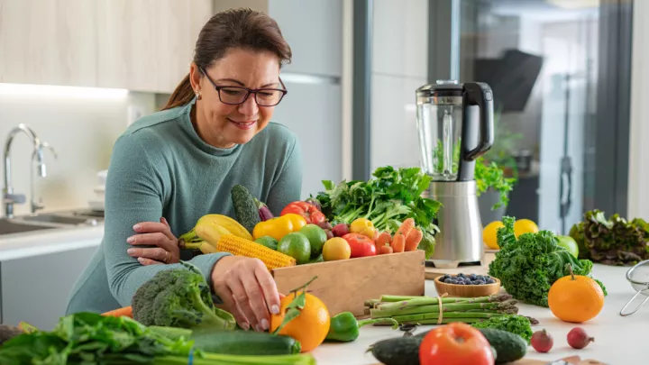 Older woman with a counter full of fruits and vegetables