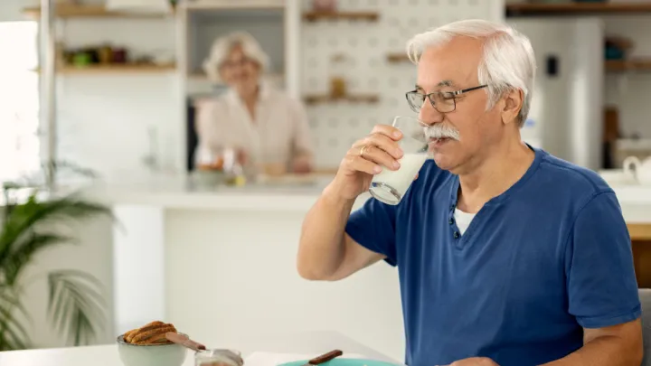 Man drinking milk at breakfast table