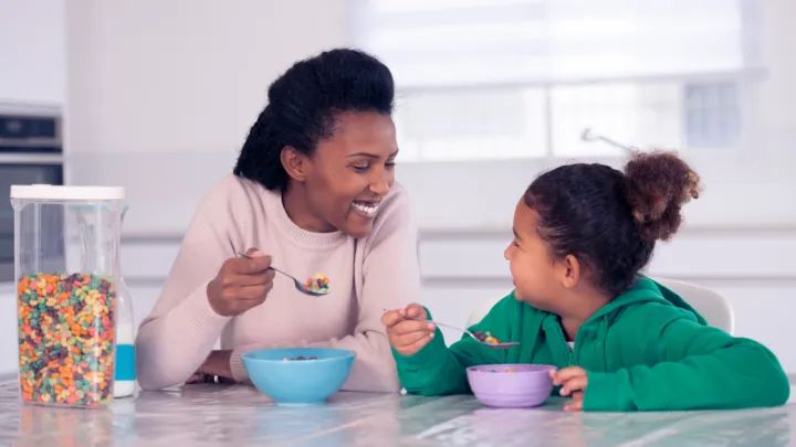 Woman and her daughter eating colorful cereal