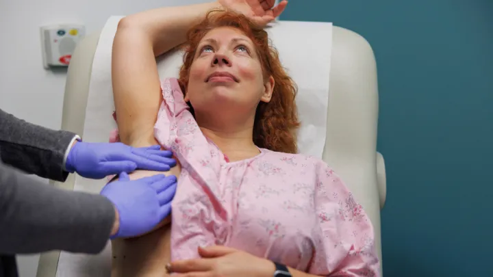 Doctor feeling woman's lymph nodes near breast
