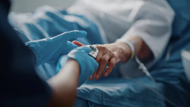 Medical provider in a gloved hand holding another hand