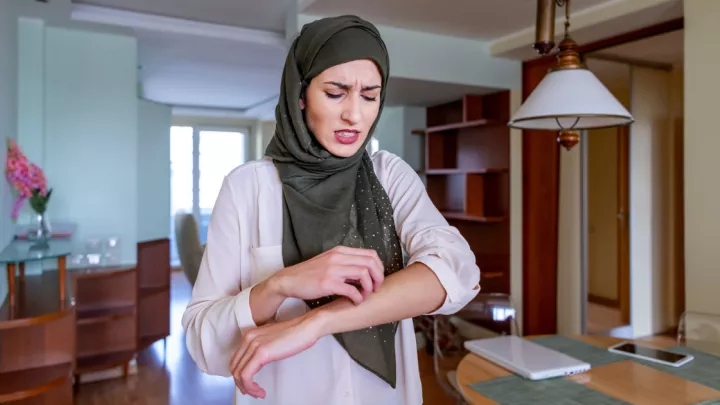 Woman wearing a hijab scratching her forearm