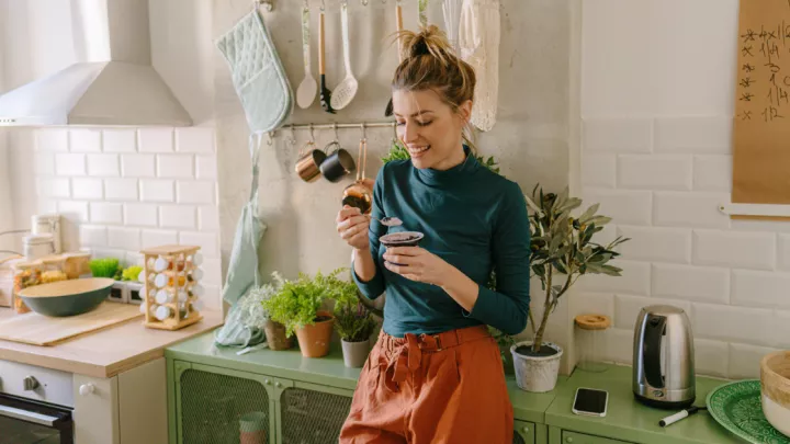 Woman standing in her kitchen eating