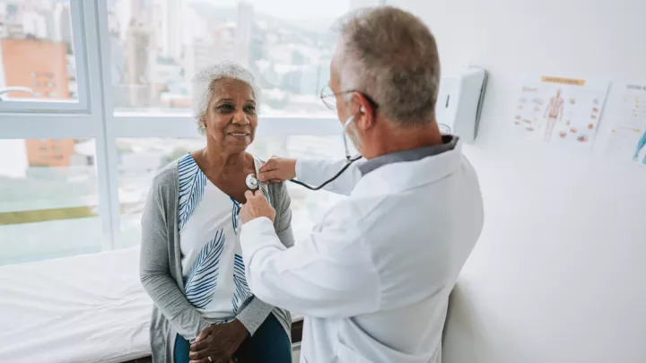 Doctor listening to older woman's heart