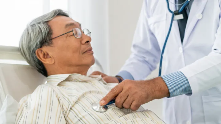 Doctor listening to man's heart