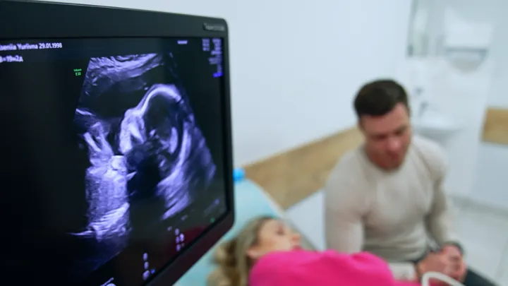 Pregnant woman receiving ultrasound with man sitting next to her