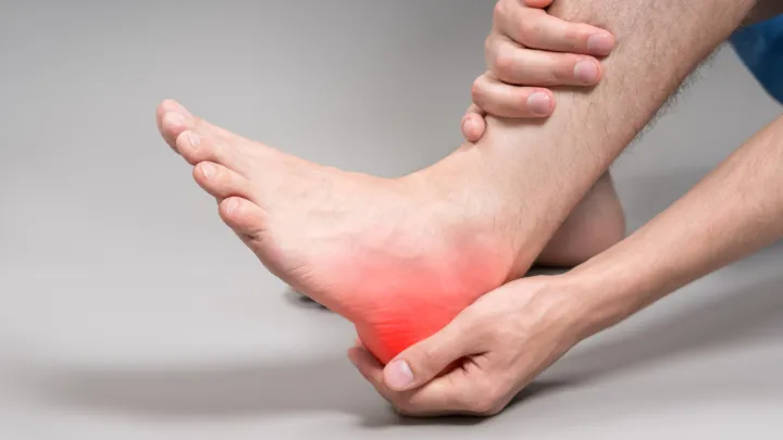 Close up of man holding his heel in pain