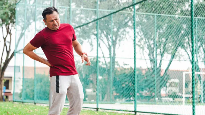 Man at park, holding hip in pain