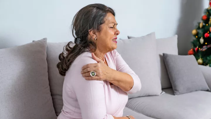 Older woman holding her shoulder in pain