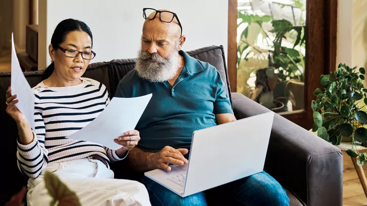 Man and woman sitting on couch looking at paperwork