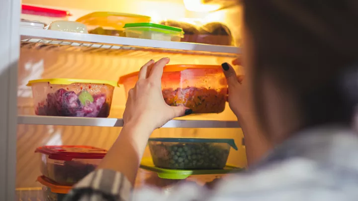 Woman reaching for Tupperware containers in her fridge