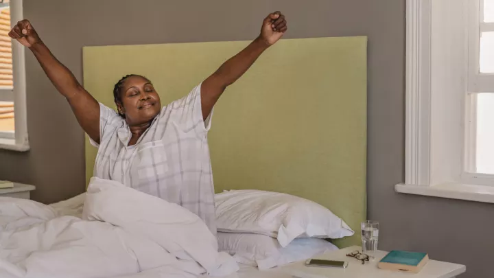 Woman in bed stretching arms