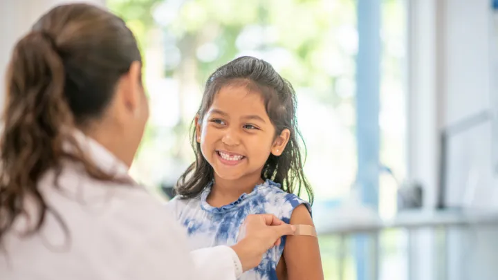 Doctor putting bandaid on little girl's arm