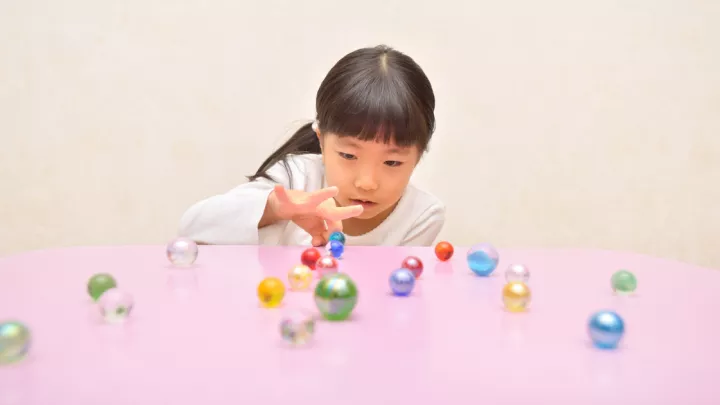 Young girl playing marbles