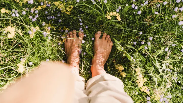 POV looking down at woman's bare feet standing in grass