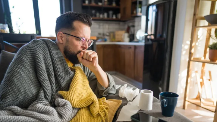 Man sitting on couch, coughing
