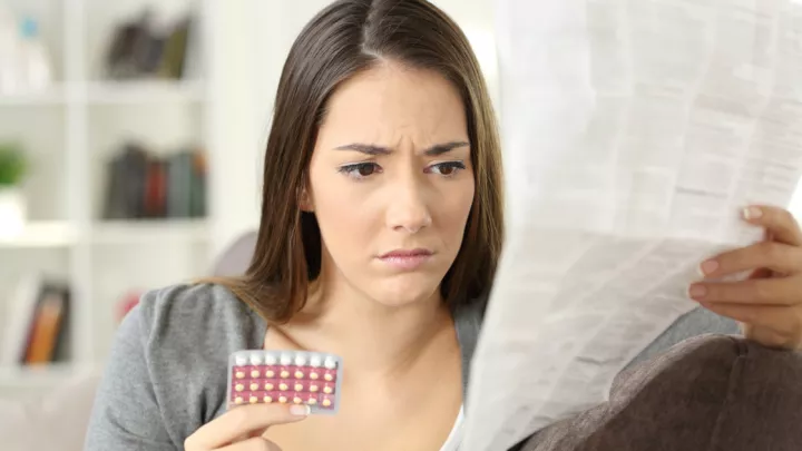 Woman looking at birth control pills