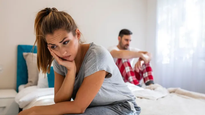 Woman and man sitting apart on bed
