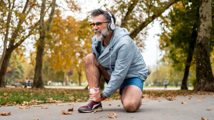 Man kneeling, holding his ankle in pain