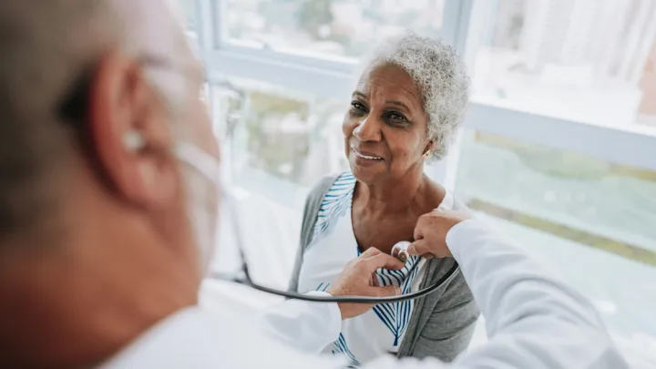 Portrait of a doctor listening to an elderly woman patient's heartbeat