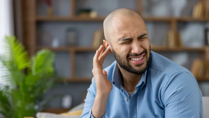 Man holding ear in discomfort